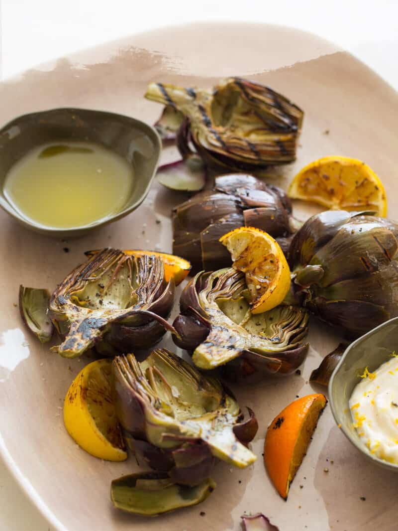 A close up of grilled artichokes with clarified butter and roasted garlic aoli.