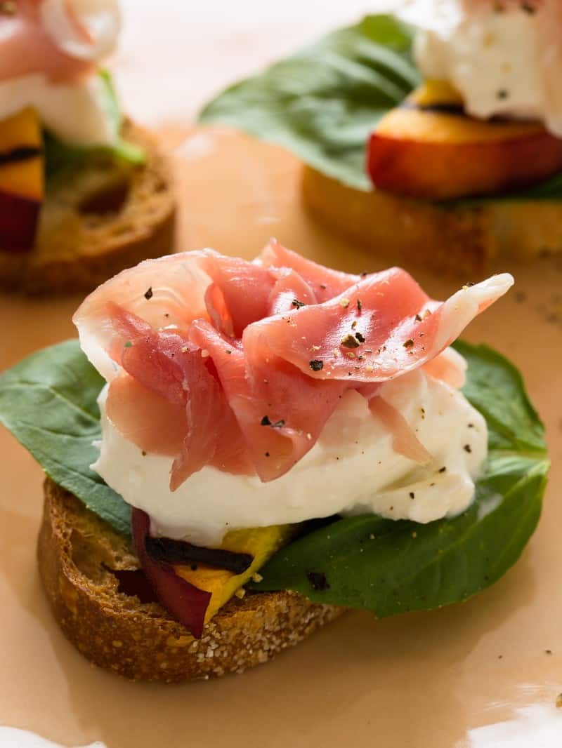 A close up of grilled peach and burrata crostini.