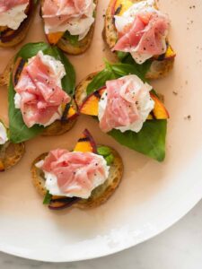 Grilled peach and burrata crostini on a platter.