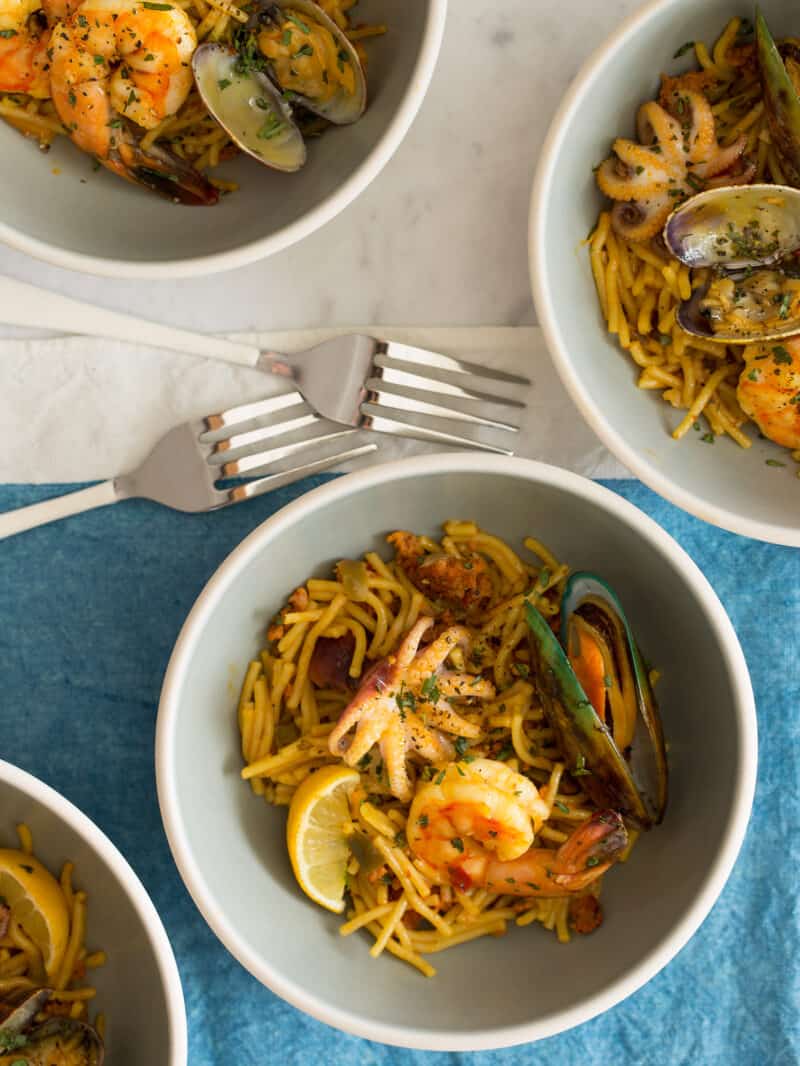 Seafood Fideau in four bowls with two forks.