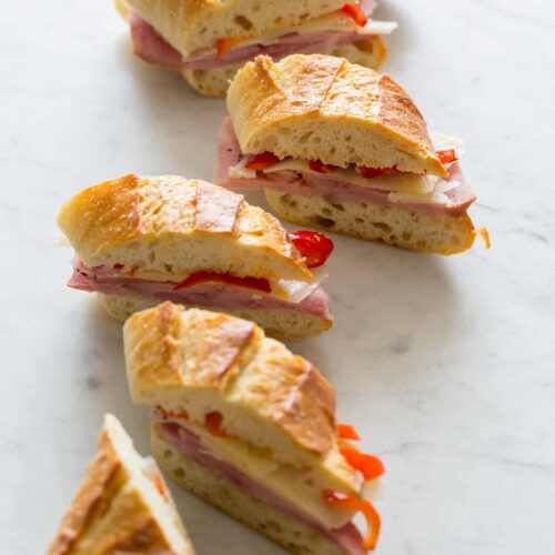 Several bocadillo bites of ham, cheese, and pickled cherry peppers on a baguette.