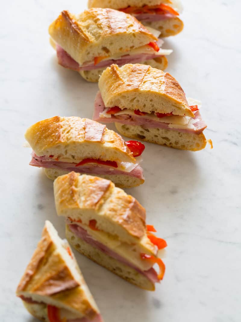 Several bocadillo bites of ham, cheese, and pickled cherry peppers on a baguette.
