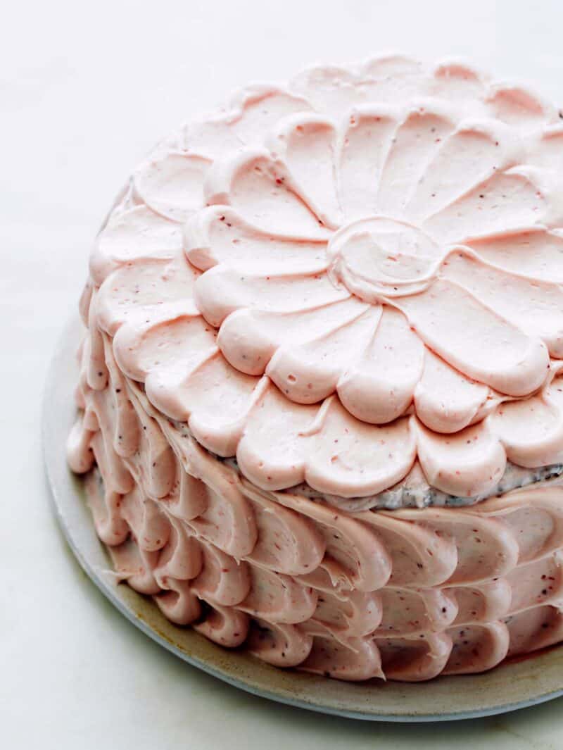 A close up of a whole devils food cake with real strawberry frosting.