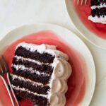 Slices of devils food cake with real strawberry frosting on plates with forks.