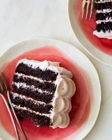 Slices of devils food cake with real strawberry frosting on plates with forks.