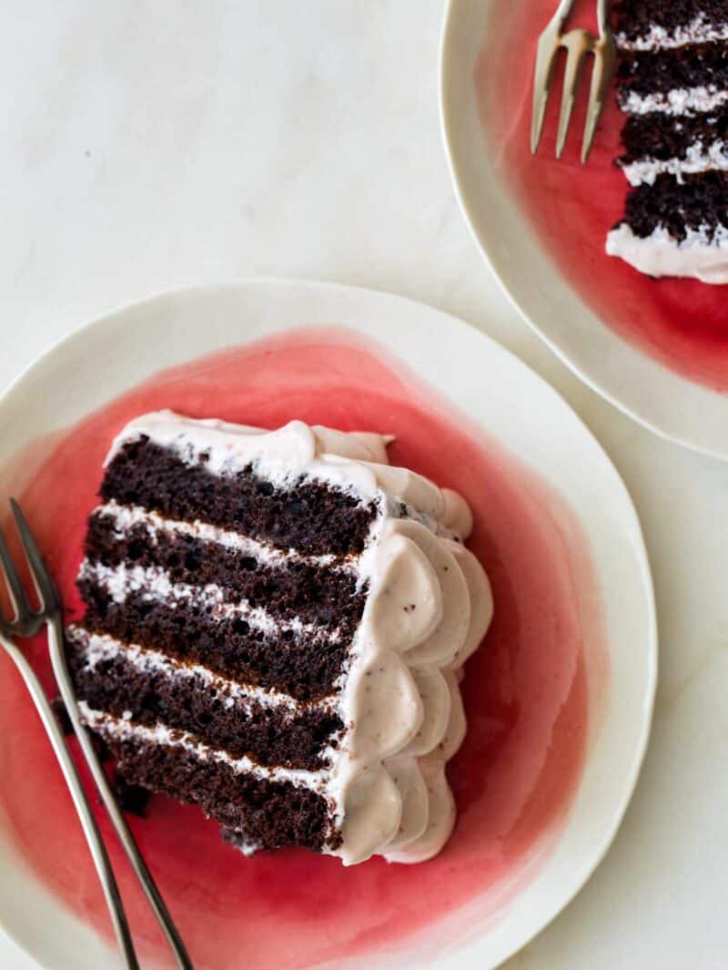 Slices of devils food cake with real strawberry frosting on plates with forks.