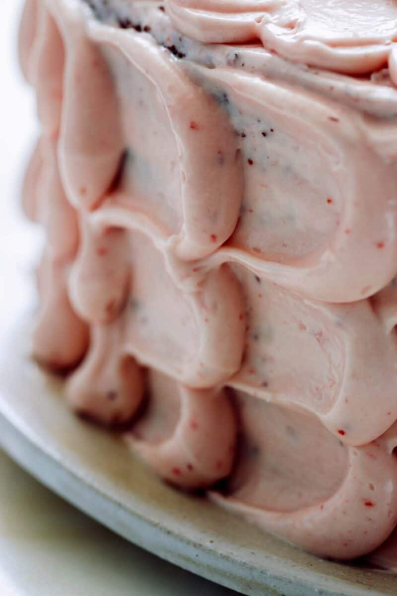 A close up of real strawberry frosting  on a devils food cake.