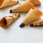A close up of homemade ice cream cones on a marble countertop.