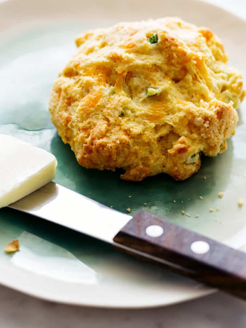 Jalapeno and cheddar cornmeal biscuits with a butter knife and butter on the side.
