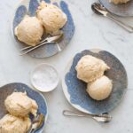 Several plates of salty nuts ice cream scoops with spoons and a ramekin of salt.