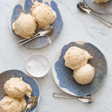 Several plates of salty nuts ice cream scoops with spoons and a ramekin of salt.