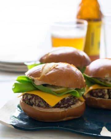 A close up of several big veg quinoa burgers with plates and beer.