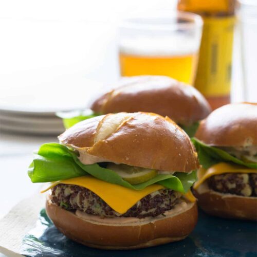 A close up of several big veg quinoa burgers with plates and beer.