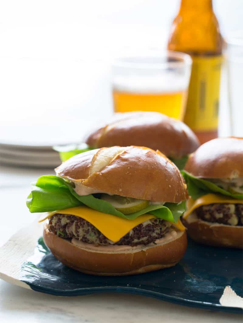 A close up of several big veg quinoa burgers with plates and beer.