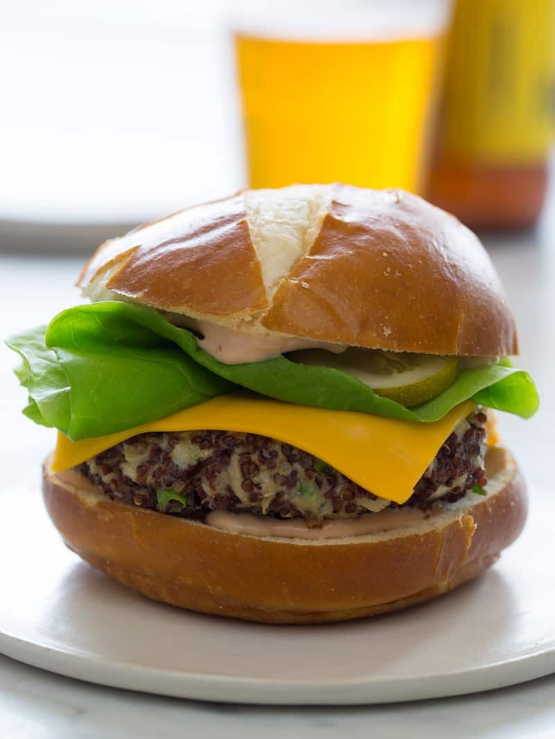 A vegetarian cheeseburger on a plate with beer in the background.