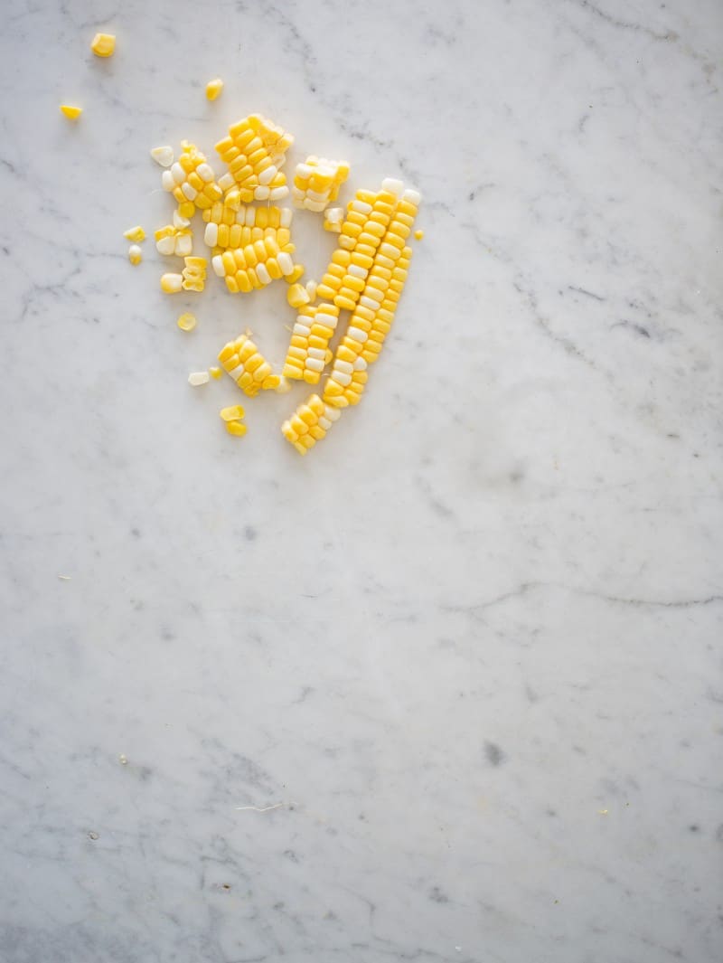 Fresh corn cut off the cob on a marble countertop.