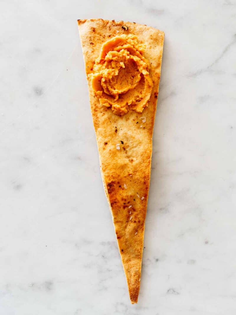 A dollop of pumpkin hummus on a seasoned pita chip