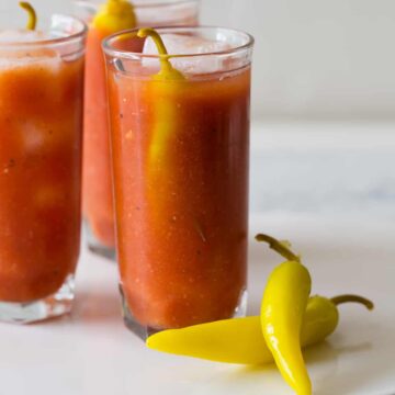 Several simple bloody marys garnished with pickled peppers.