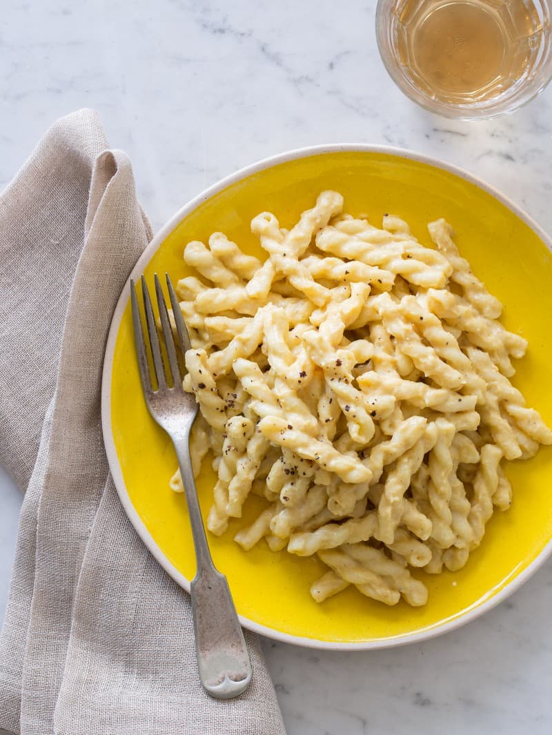 A plate of vegan cauliflower cream sauce on pasta with a fork and napkin.