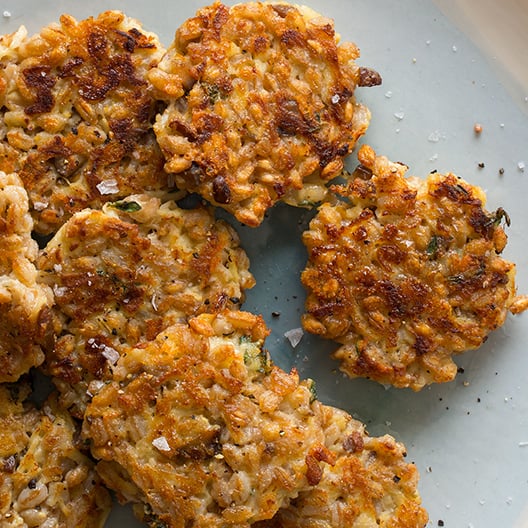 A close up of cheesy apple farrow cakes on a light blue plate.