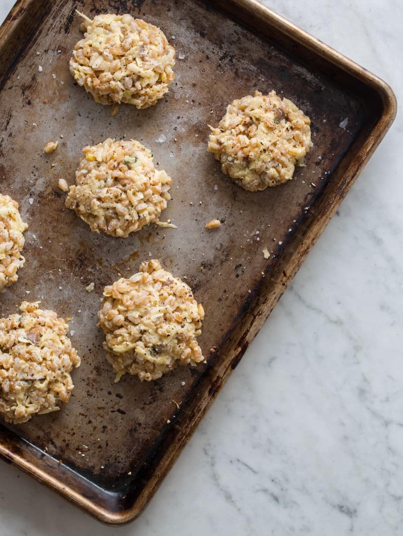 A sheet pan with uncooked cheesy apple faro cakes.