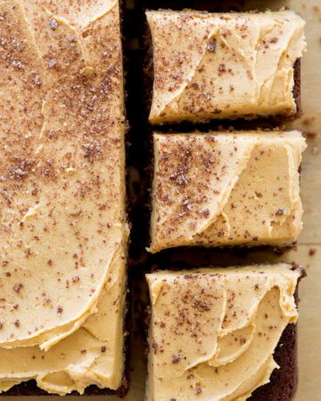 A close up of spicy chocolate stout cake with peanut butter buttercream with square pieces cut.