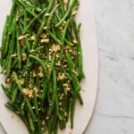 A platter of lightly roasted green beans with parmesan almond crumble.