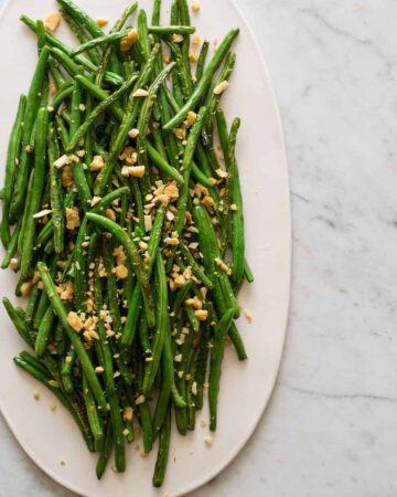 A platter of lightly roasted green beans with parmesan almond crumble.