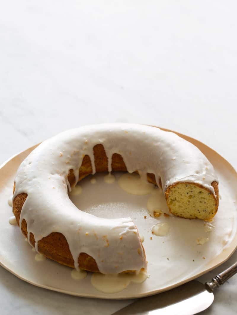 A ring shaped meyer lemon and poppyseed pound cake with a piece cut out.