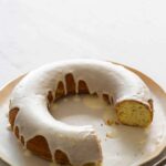 A meyer lemon and poppy seed ring shaped pound cake with a piece cut out.