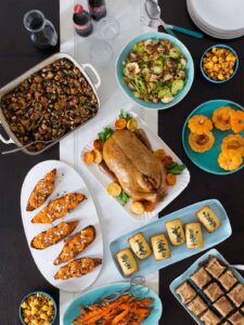 A table top view of platters and serving bowls full of non traditional Thanksgiving recipes.