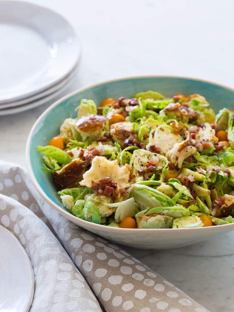 A bowl of shaved Brussels sprouts salad with a warm prosciutto mustard vinaigrette. 
