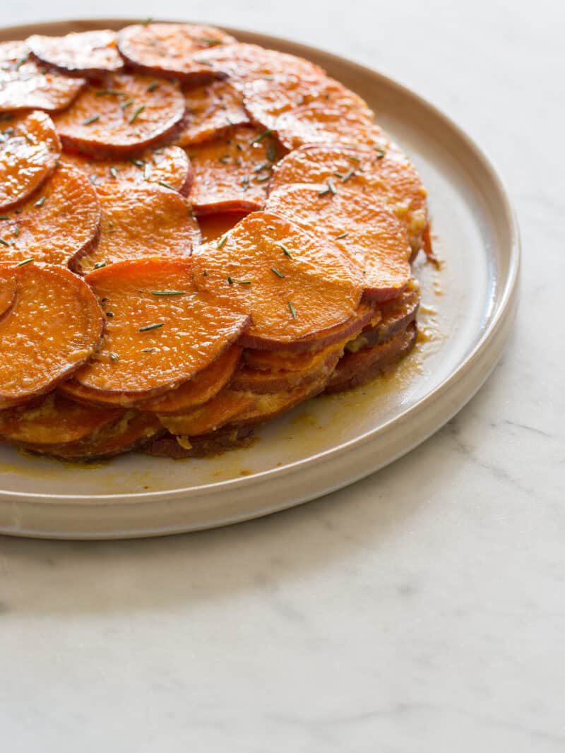 A close up of sweet potato and rosemary gratin on a plate.