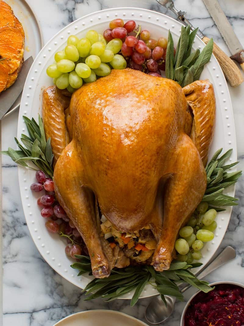 Thanksgiving turkey on a platter garnished with grapes and herbs.