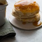 A close up of apple cinnamon pancakes with brown sugar buttermilk syrup.