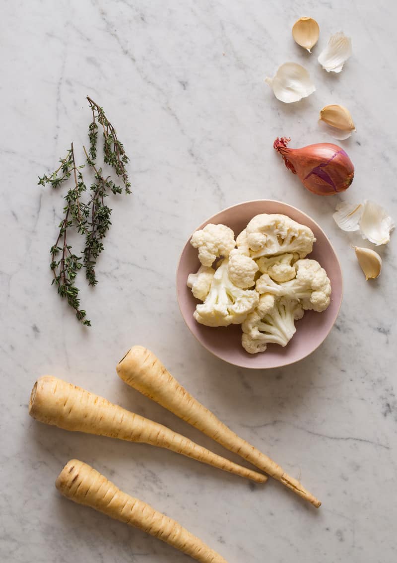 Ingredients for roasted cauliflower parsnip soup on a marble countertop.