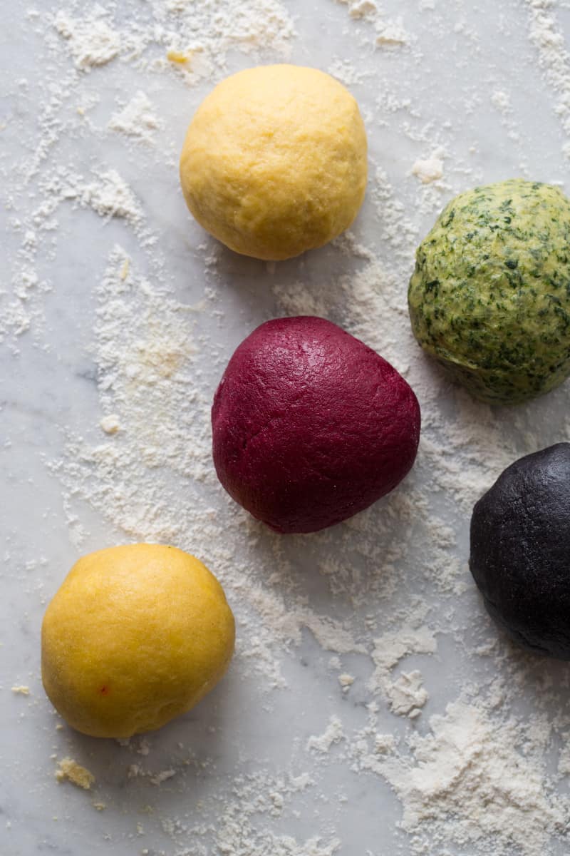 A close up of a variety of colorful pasta dough balls.