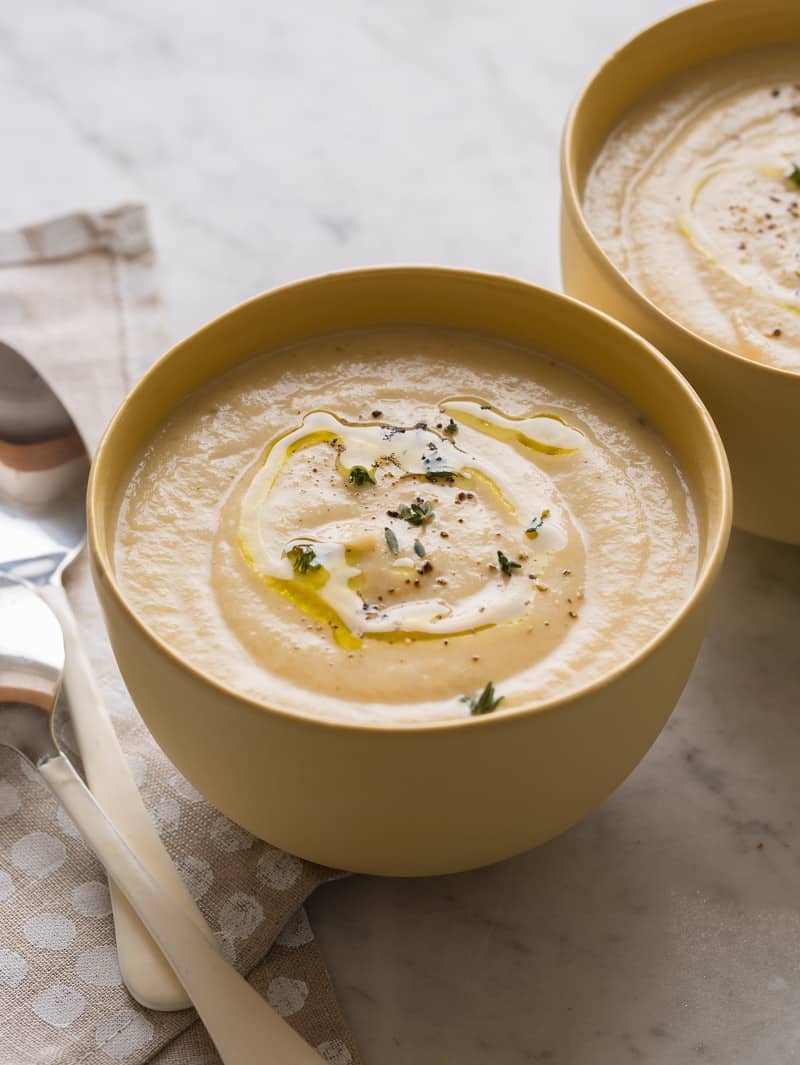 Bowls of roasted cauliflower parsnip soup with a spoon.