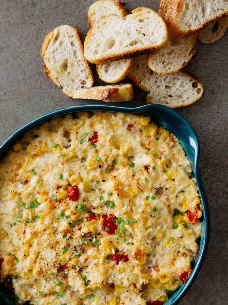 A close up of a dish of hot crab dip with crostini on the side.