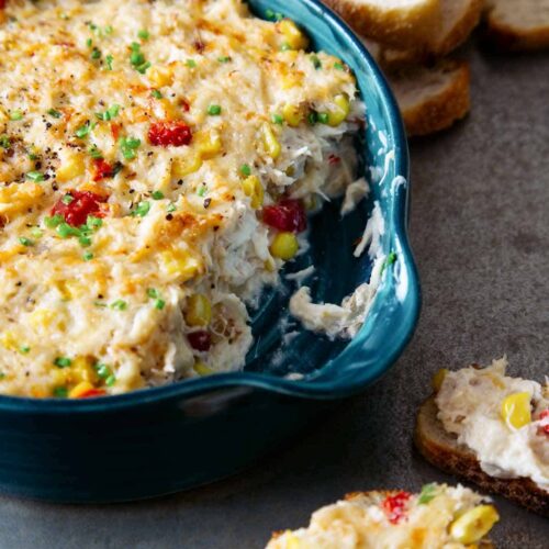 A close up of a dish of hot crab dip with dipped crostini.