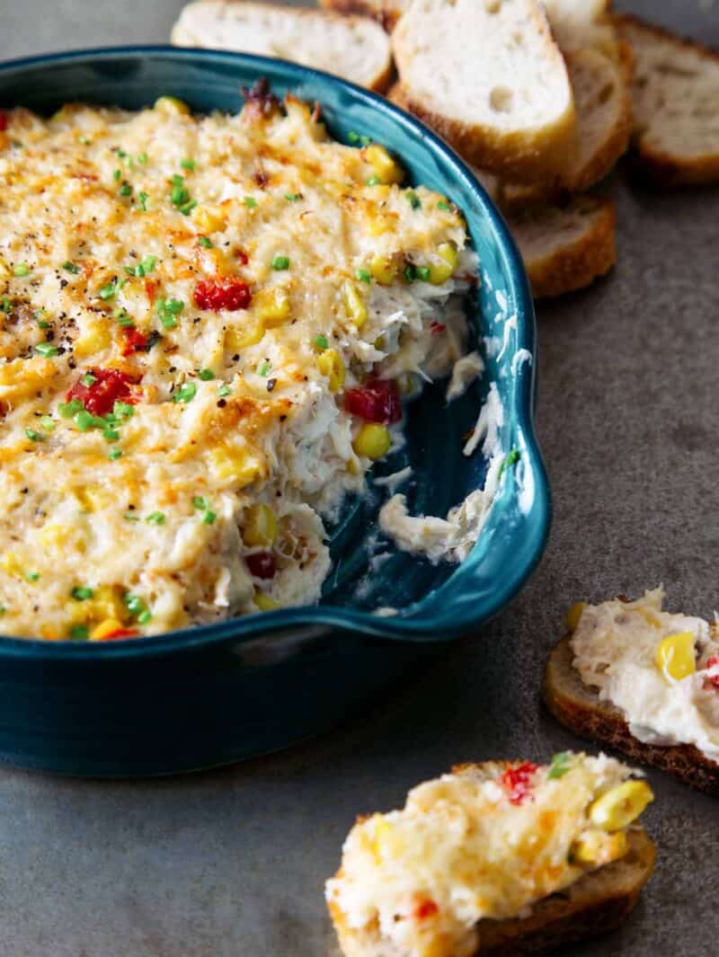 A close up of a dish of hot crab dip with dipped crostini.