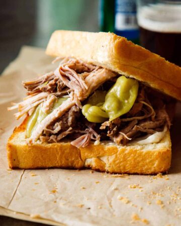 A close up of a slightly opened slow cooker pickled pulled pork sandwich.