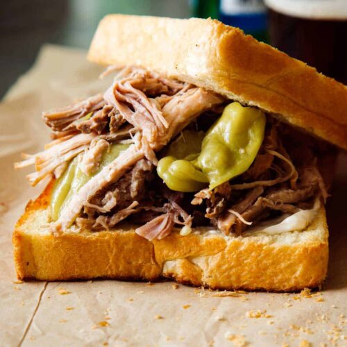 A close up of a slightly opened slow cooker pickled pulled pork sandwich.