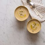 Roasted cauliflower parsnip soup in bowls next to napkins and spoons.