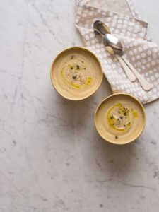 Roasted cauliflower parsnip soup in bowls next to napkins and spoons.