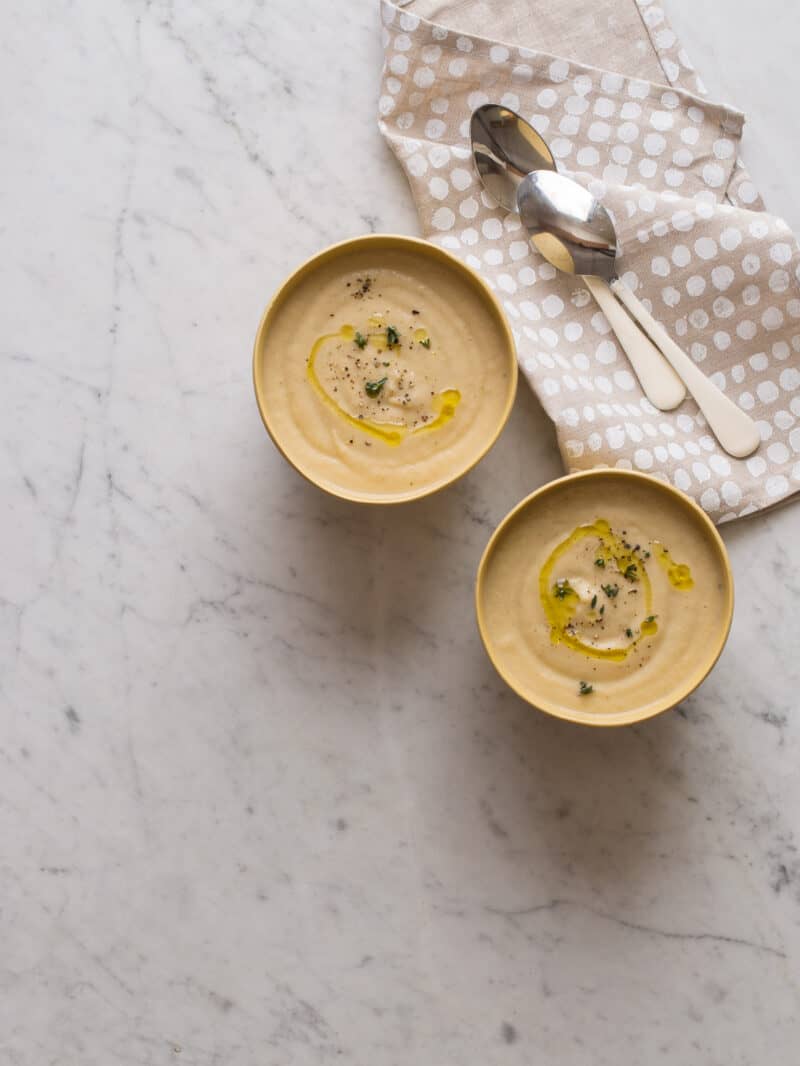 Roasted cauliflower parsnip soup in bowls with spoons and napkins.