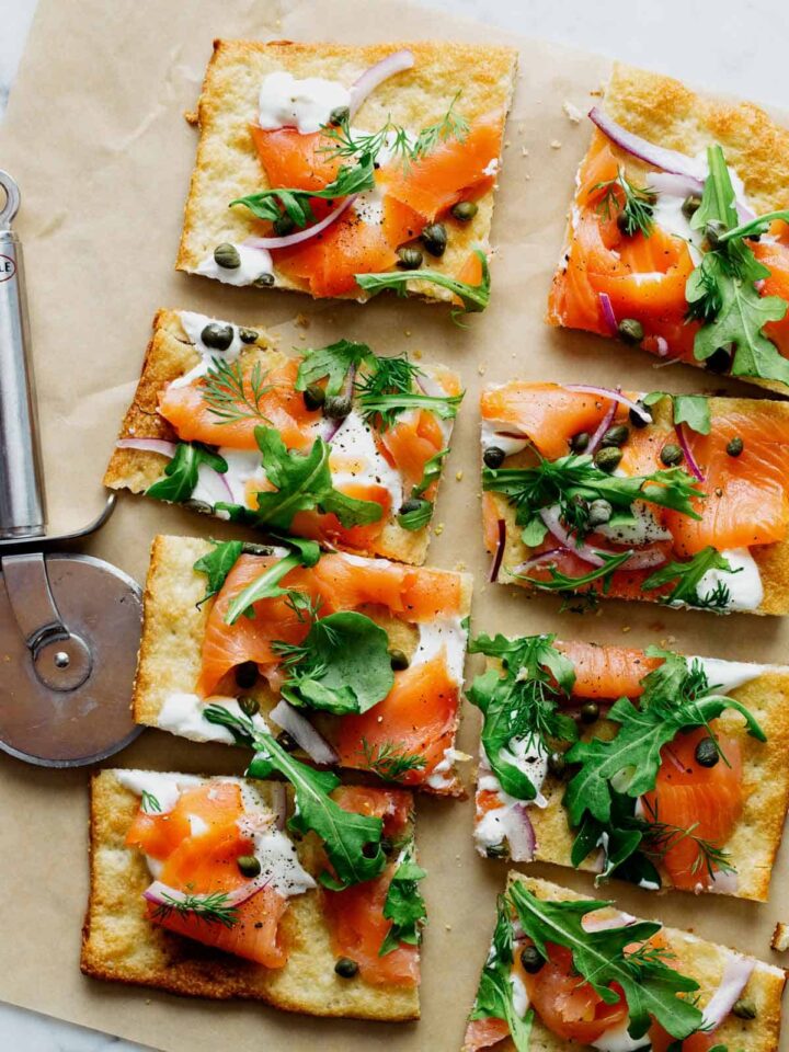 A sliced smoked salmon pizza with a pizza cutting wheel.
