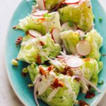 A close up of a wedge salad on a turquoise plate.