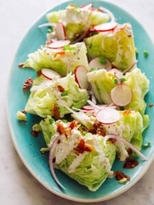 A close up of a wedge salad on a turquoise plate.