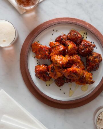 A plate of Korean fried chicken nuggets with drinks.